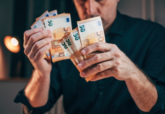 Businessman counting fifty euro banknotes in office while working overtime