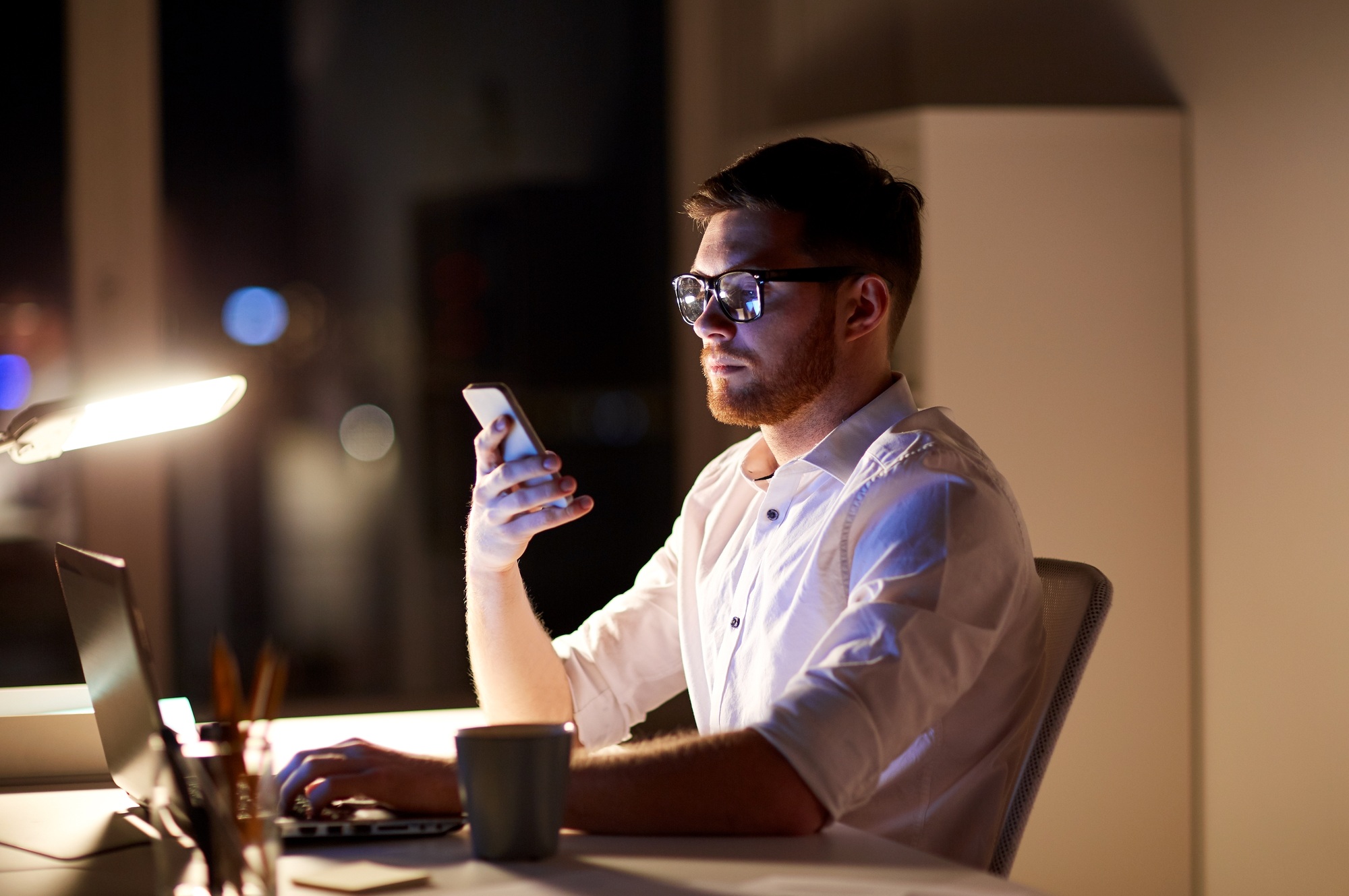 businessman texting on smartphone at night office