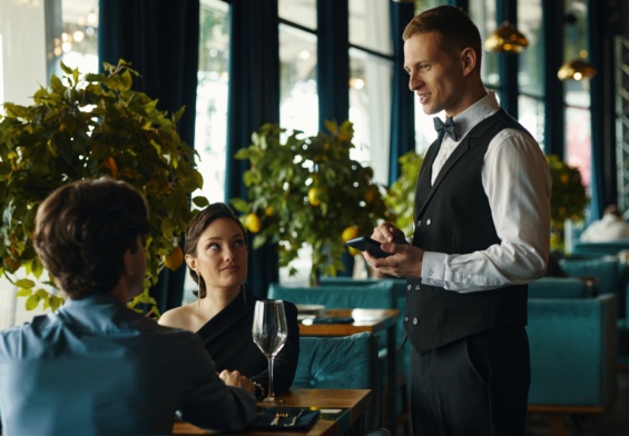 Caucasian Young Adult Waiter Taking Order from Multiethnic Couple in Restaurant