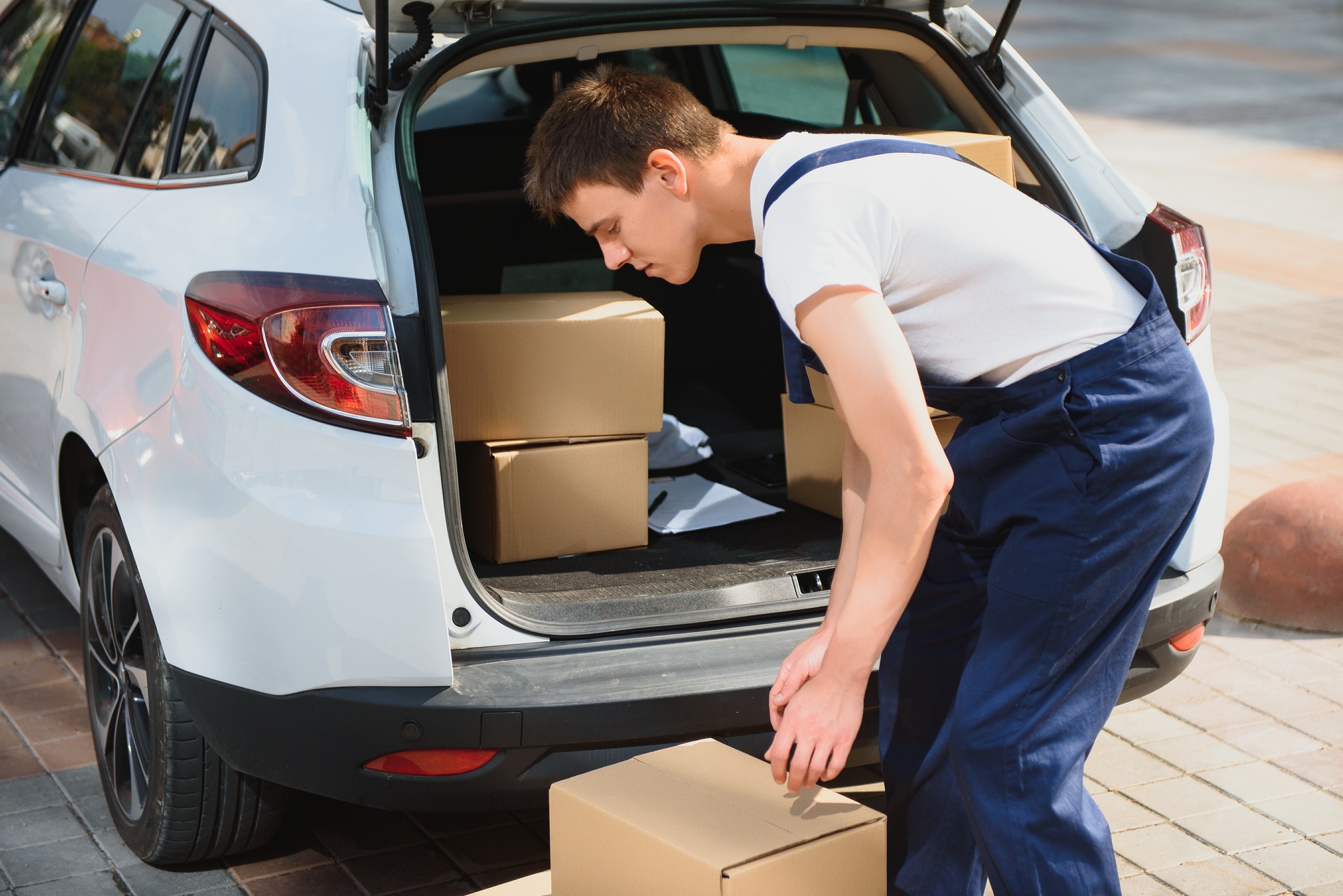 Deliveryman holds parcels at the car, delivering