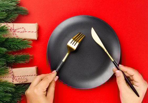 gold cutlery with black handles crossed over black plate on red table the concept of New Year dinner