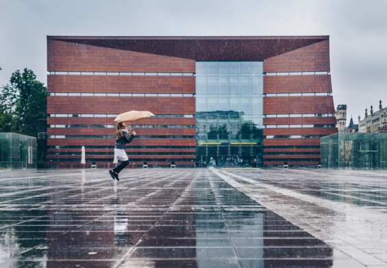 Scenic view of a little girl jumping with an umbrella in rain in Freedom Square, Poland