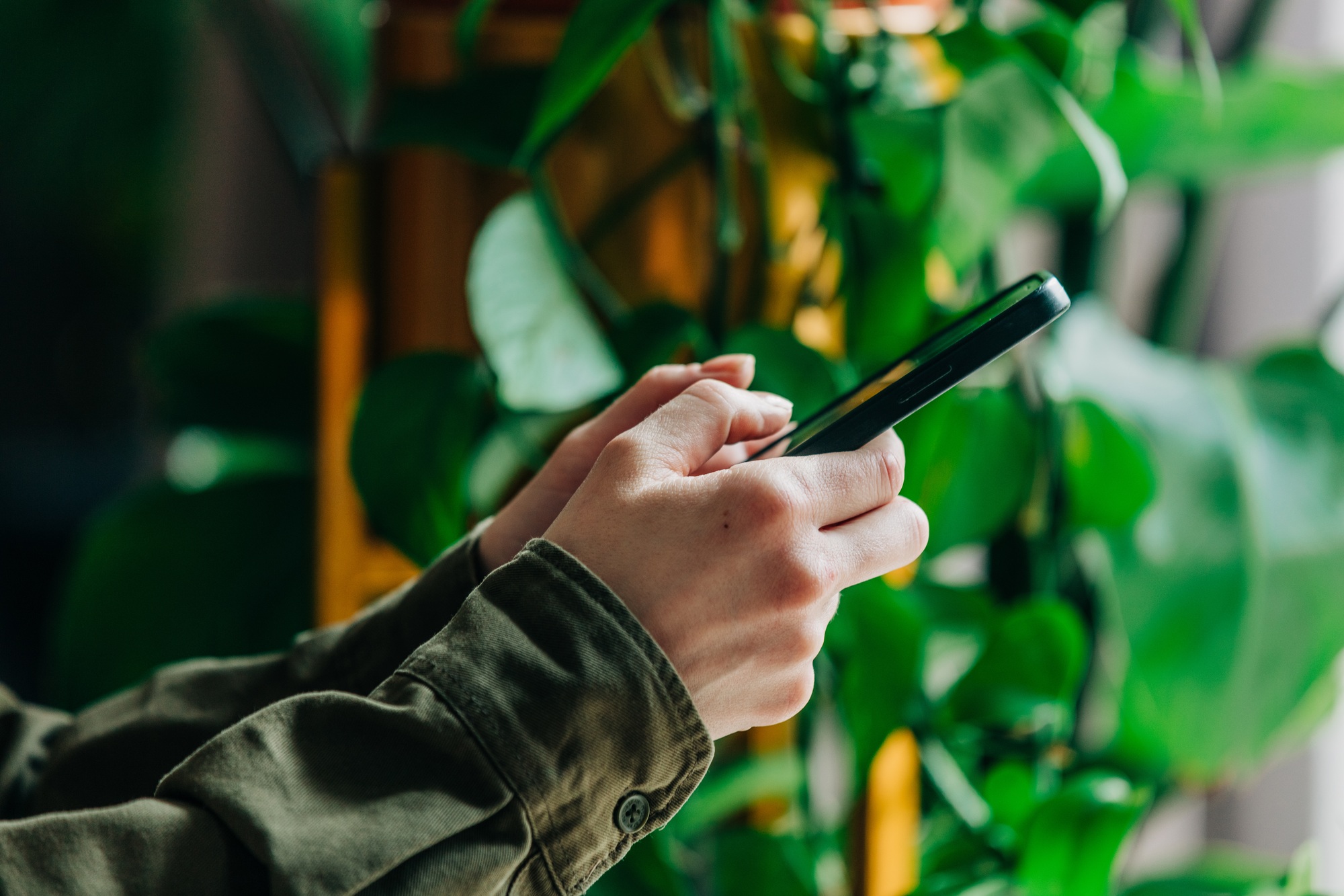 Woman in green shirt holds smartphone in hand